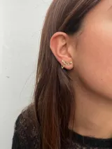 Par de aros dorados con forma geométrica y pequeños brillantes, unidos por una cadena fina.