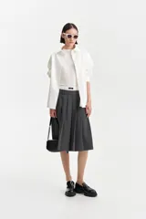 Camisa blanca de algodón con corte amplio y abotonadura frontal. Presenta un pequeño detalle bordado en un costado del frente.