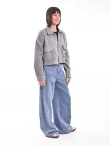 Chaqueta corta gris jaspeado con cuello camisero, cierre frontal con botones a presión, bolsillos de parche con solapa en el pecho y mangas largas.