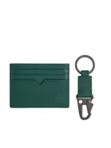 Set de regalo Tommy Hilfiger que incluye un tarjetero y un llavero a juego, ambos confeccionados en cuero con textura Saffiano de color verde oscuro. El tarjetero cuenta con múltiples ranuras para tarjetas y el escudo TH grabado en relieve en la parte frontal. El llavero posee un cierre de pinza metálico y una anilla con el logo de la marca grabado.