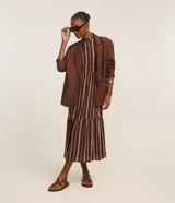 Vestido midi evasé sin mangas, confeccionado en viscosa, con cuello alto, corte en la cintura, recortes fruncidos en la pollera y rayas verticales desencontradas.