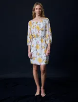 Vestido corto de gasa estampada con flores amarillas, marca Sandra Darren. Tiene escote redondo, mangas 3/4 con puño elastizado y lazo de ajuste en la cintura.