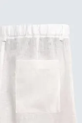 Pantalón de corte relajado confeccionado en tejido de lino color beige claro. Cuenta con cintura elástica, bolsillos frontales, bolsillos traseros de plastrón y cierre frontal con cremallera y botón.