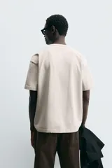 Camiseta blanca de algodón compacto, corte relaxed fit, cuello redondo y mangas cortas.