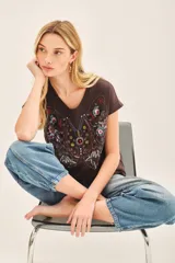 Remera marrón de jersey flamé con calce suelto y bordado frontal centrado con diseño de mariposa y flores.