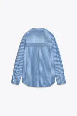 Camisa celeste con rayas verticales blancas, de corte holgado, cuello solapa, escote pico y mangas largas con puños abotonados.
