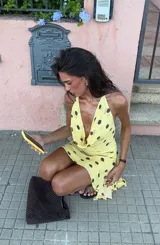 Vestido corto amarillo con lunares marrones, escote drapeado y tirantes finos.