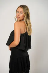 Blusa negra con un hombro descubierto y manga larga con volados.