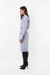 Camisa celeste crop confeccionada en poplín de algodón, con terminación al corte para que desfleque. Acceso a la prenda mediante cartera de botones, cuello y puño reforzado. En canesú de espalda detalle de bordado aplique al corte de logo TW.