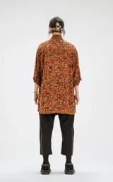 Camisa de manga corta color marrón con estampado geométrico en negro y blanco, calce oversize y canesú en la espalda.