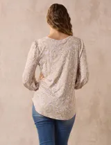 Blusa estampada color beige con cuello redondo calado y mangas 3/4 abullonadas con terminación elastizada.