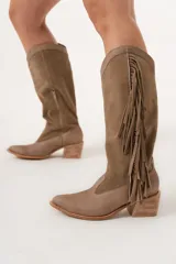 Bota texana de caña alta color visón, 100% cuero hecha a mano en Uruguay, con cierre lateral y taco de 5,5 cm. Tiene flecos en los costados internos.