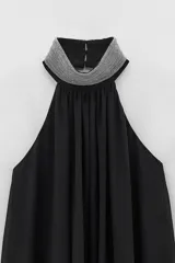 Vestido corto negro con cuello halter con joyas, caída amplia y espalda descubierta.