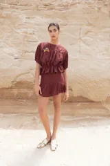 Blusa color chocolate con cuello redondo, mangas cortas abullonadas, detalle de flores bordadas en el frente y corte con volantes en la cintura.