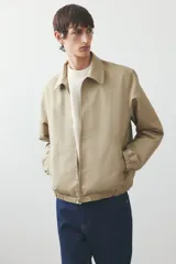 Campera color beige de denim rígido con cuello clásico, cierre frontal, bolsillos insertados al bies y un bolsillo interior. Elástico revestido en puños y bajo. Corte estándar y forrada.