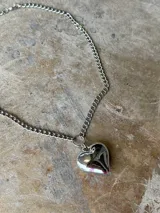 Collar plateado con cadena de eslabones y dije de corazón inflado.