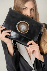 Cartera de mano tipo sobre, color negro, con solapa frontal decorada con una rodaja de ágata natural con bordes metálicos.