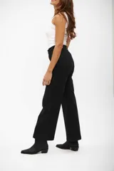 Jean de corte wide leg en color negro, con tiro alto y costuras verticales decorativas en el frente. Cuenta con cierre y botón metálico.