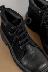 Borcegos negros de cuero charol, con punta cuadrada, cordones y suela track.