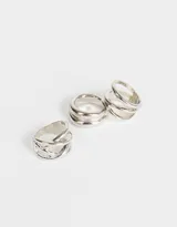 Set de tres anillos dorados de metal con diferentes diseños: uno con tres aros abiertos, otro con tres aros lisos y otro con dos aros lisos.