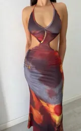 Vestido largo con estampado abstracto en tonos marrones, rojos y grises. Diseño ajustado con escote halter y aberturas laterales en la cintura.