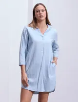 Vestido camisero corto celeste de algodón y viscosa, con cuello camisero, escote en V, mangas tres cuartos con botón y bolsillos laterales.