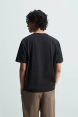 Camiseta blanca de algodón de peso medio, corte recto, cuello redondo y mangas cortas.