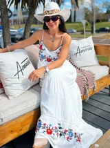Vestido largo blanco con breteles finos y bordados de flores en el escote y el ruedo.