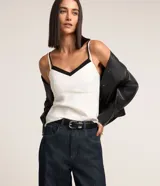 Blusa de breteles finos color blanco con escote en V y superposición contrastante en negro, confeccionada en crepé.