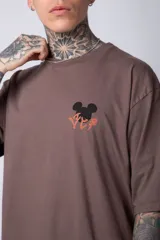 Remera blanca de algodón de corte oversize con mangas cortas y cuello redondo. Presenta un pequeño estampado en el frente con la figura de Mickey Mouse y caracteres orientales.