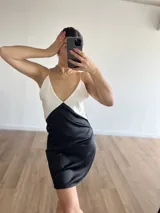 Vestido corto de satén con breteles finos, corte al cuerpo y diseño color block en blanco y negro.