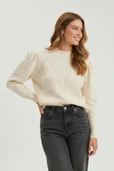 Sweater acrílico color natural, con cuello redondo, diseño de fantasía y corte ajustado al cuerpo. Presenta mangas largas abullonadas con detalles de punto en relieve.