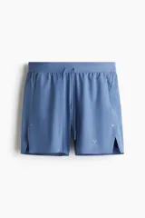 Short deportivo azul con calza biker interna, confeccionado en tejido funcional DryMove™ que ayuda a absorber el sudor. Cuenta con cintura elástica con cordón de ajuste, bolsillos laterales con cierre, abertura lateral en el bajo y logo estampado en la pierna.
