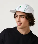 Gorra blanca de cinco paneles con visera plana y ribetes verdes. Presenta un estampado con un pez koi, texto en japonés y la palabra "Tokyo" en verde.