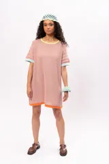 Vestido corto tipo remerón color rosa, de tejido de punto con cuello redondo y mangas cortas. Presenta ribetes en color amarillo en el cuello, celeste en las mangas y naranja en el ruedo.