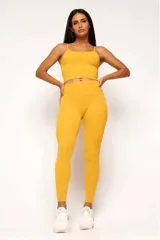 Conjunto deportivo color mostaza compuesto por un top corto de tirantes finos y calzas largas de cintura alta.