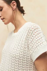 Chaleco tejido color beige con diseño calado, cuello redondo y mangas cortas.