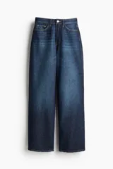 Pantalón de jean azul oscuro, de tiro alto, corte recto y pierna ancha. Diseñado para siluetas con curvas, ceñido en la cintura y holgado en cadera y muslos. Confeccionado en denim de algodón rígido y cuenta con cinco bolsillos.