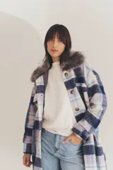 Tapado largo con estampado de cuadros en tonos azul, celeste y blanco. Tiene cuello de piel sintética gris, cierre con botones y bolsillos laterales.