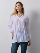 Blusa blanca de manga larga con cuello a la base y escote en V con botones. Terminación de manga con elástico.