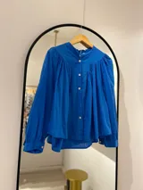 Camisa azul francia de manga larga con puño, cuello mao y cierre frontal con botones.