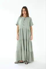 Vestido largo color verde salvia, de lino, con cuello mao, mangas cortas y corte escalonado con volados.