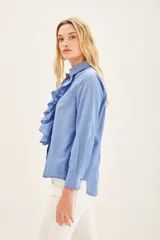 Camisa celeste de manga larga con volados en el frente y cuello clásico.