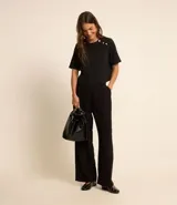 Blusa negra de crepé con cuello redondo, mangas cortas y botones decorativos dorados en los hombros.