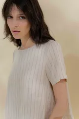 Blusa de lino color beige con rayas verticales negras, corte recto, escote redondo y mangas cortas.