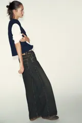 Prenda de manga larga blanca con un chaleco de tejido de punto azul marino superpuesto, creando un efecto de dos piezas. El chaleco es de cuello redondo y corte recto.