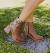 Bota corta de cuero marrón con detalle de cuero con textura de cocodrilo en el lateral y en el taco. Tiene cierre del lado interno y taco de madera forrada en cuero de 7cm.