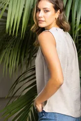 Blusa sin mangas color beige, de crepe. Cuello a la base con frunce, apertura ojal y botón.