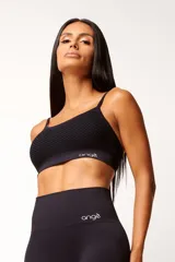 Top deportivo negro con tecnología seamless, breteles finos y textura con microtramas respirables. Cuenta con forro interno.