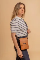 Bandolera tipo phone bag pequeña, color marrón claro, con correa de galón regulable. Tiene un compartimento principal y un bolsillo adicional con tapa.